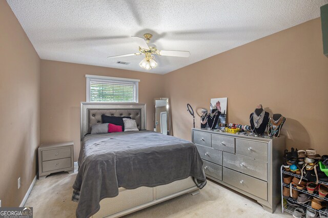 bedroom featuring light carpet, a textured ceiling, and ceiling fan