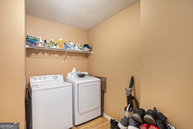 clothes washing area with separate washer and dryer, light hardwood / wood-style floors, and a textured ceiling