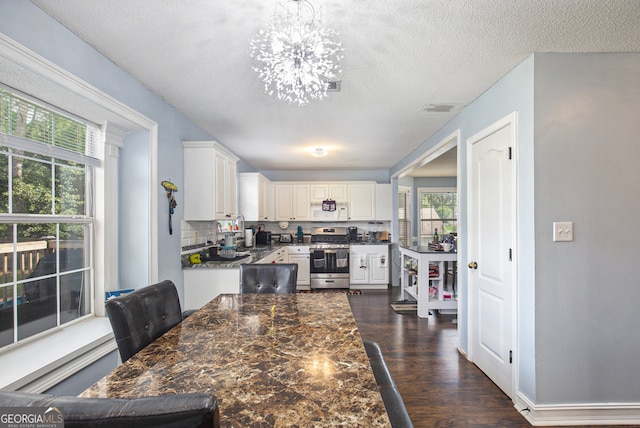 kitchen featuring white cabinetry, stainless steel range oven, dark hardwood / wood-style flooring, an inviting chandelier, and a textured ceiling