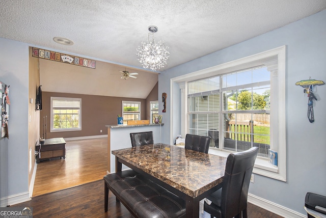 dining area featuring vaulted ceiling, a textured ceiling, ceiling fan with notable chandelier, and dark hardwood / wood-style floors