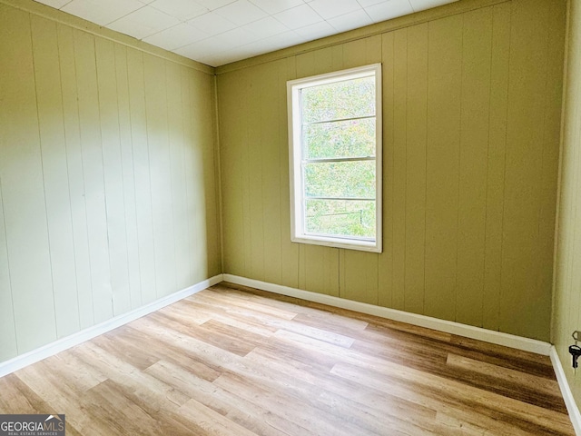 spare room featuring wooden walls and light hardwood / wood-style flooring