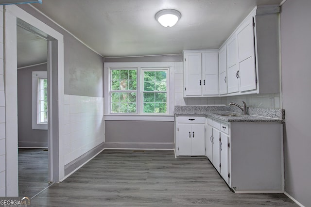 kitchen featuring crown molding, white cabinets, light wood-type flooring, light stone countertops, and lofted ceiling