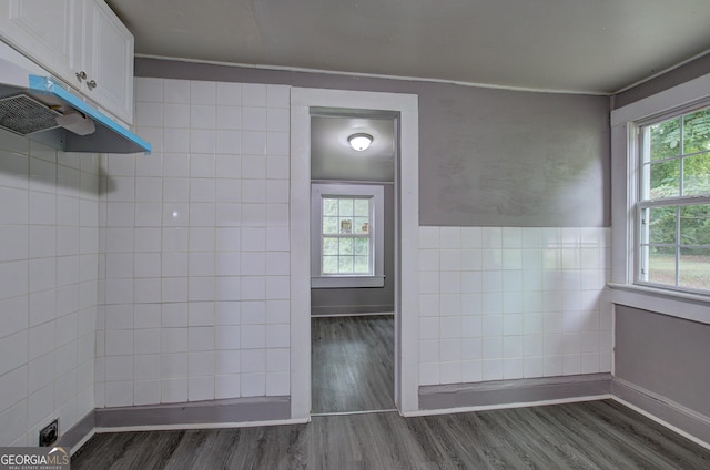 bathroom with a healthy amount of sunlight, hardwood / wood-style flooring, and tile walls