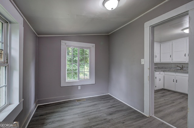 unfurnished room featuring wood-type flooring, vaulted ceiling, and ornamental molding