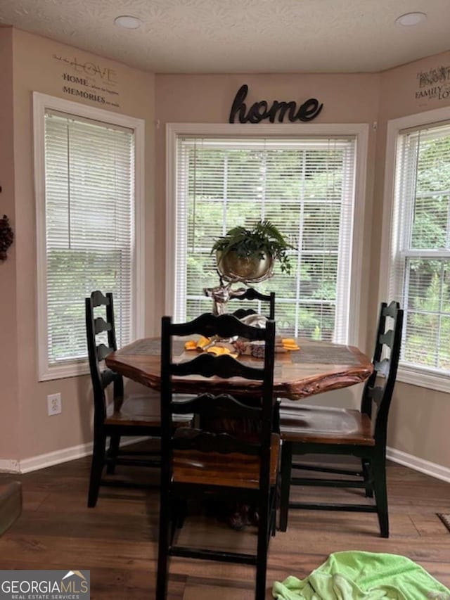 dining space featuring a textured ceiling, baseboards, and wood finished floors