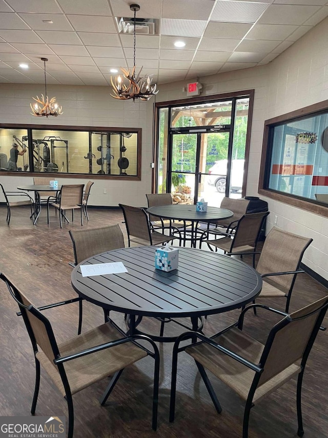 dining area with visible vents, a chandelier, a drop ceiling, and wood finished floors