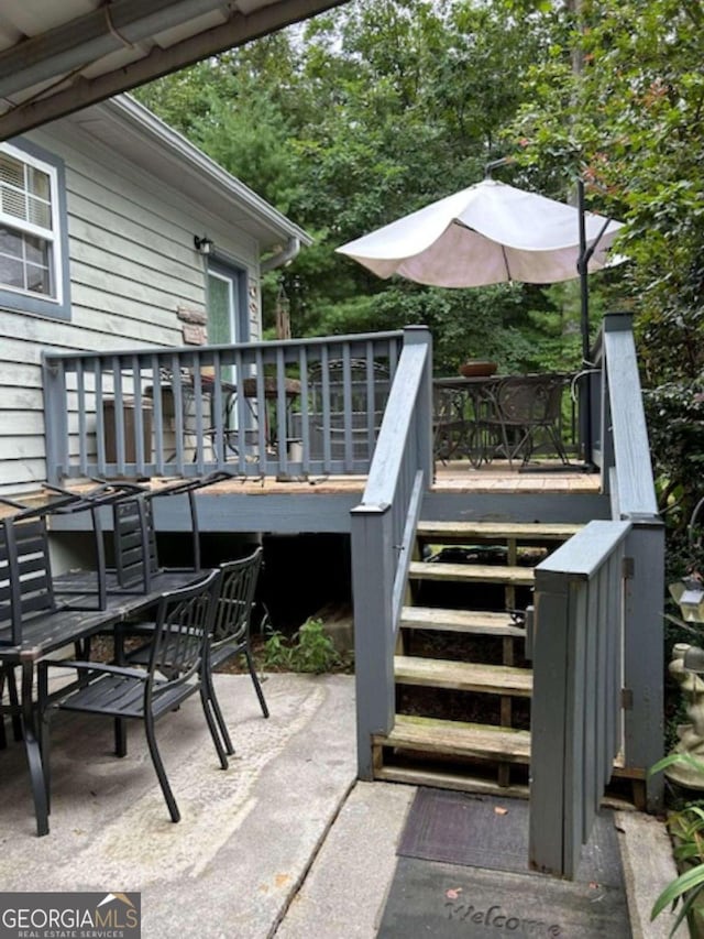 view of patio with stairway, outdoor dining area, and a wooden deck