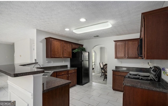 kitchen with sink, a breakfast bar area, a textured ceiling, kitchen peninsula, and black appliances