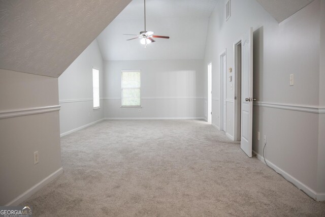 additional living space featuring ceiling fan, vaulted ceiling, light carpet, and a textured ceiling