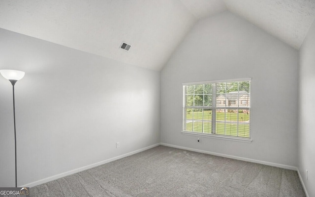 empty room with vaulted ceiling and carpet flooring