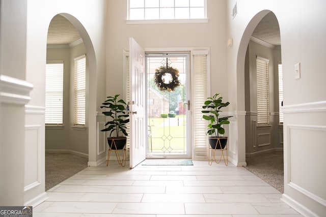 entrance foyer featuring crown molding, plenty of natural light, and light colored carpet