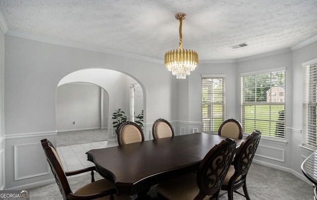 dining area featuring an inviting chandelier, ornamental molding, light colored carpet, and a textured ceiling