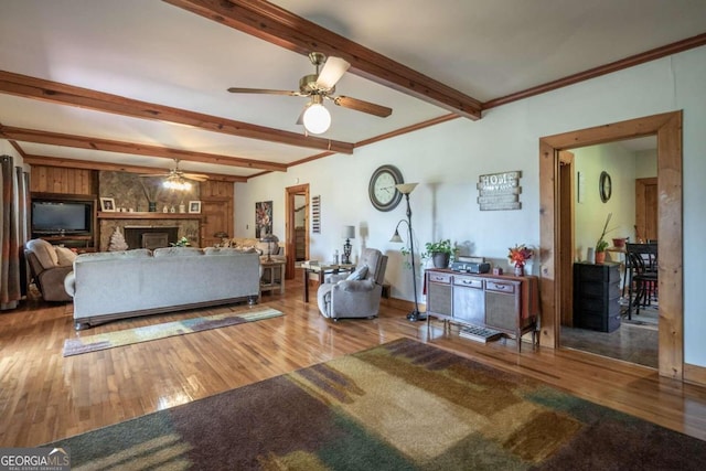 living room featuring a fireplace, ceiling fan, wood-type flooring, and beam ceiling