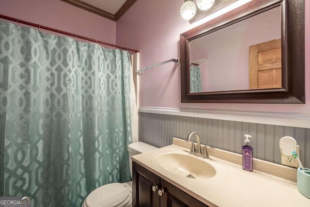 bathroom with vanity, toilet, and ornamental molding