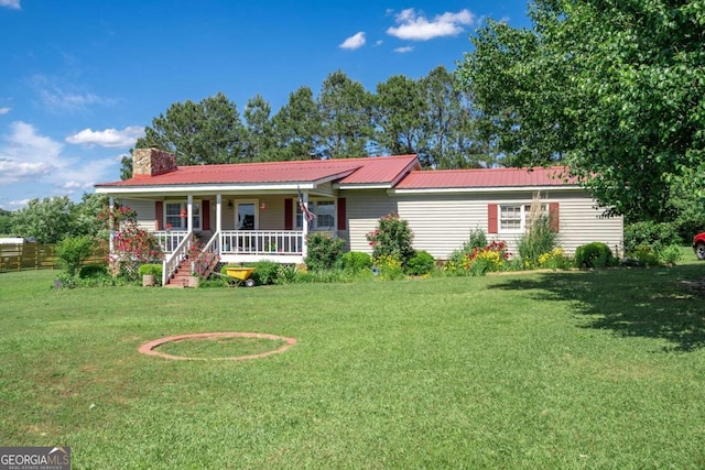 ranch-style home with metal roof, a chimney, a front lawn, and a porch