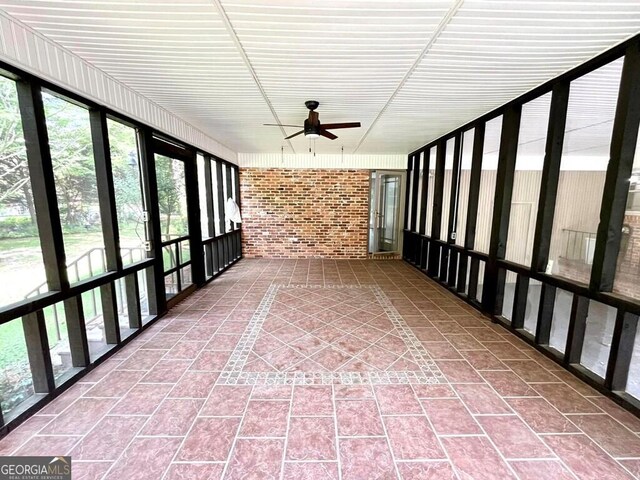 unfurnished sunroom with ceiling fan