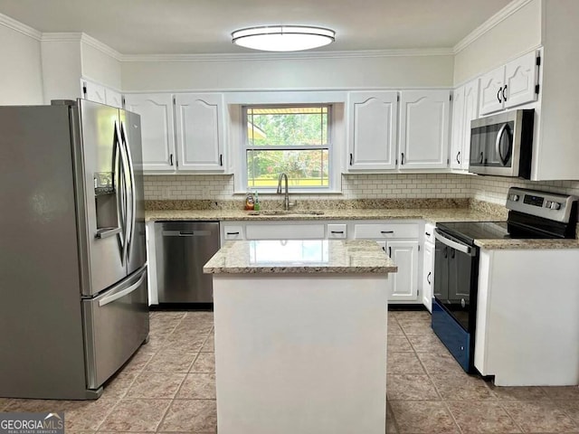 kitchen featuring sink, appliances with stainless steel finishes, white cabinetry, ornamental molding, and a kitchen island