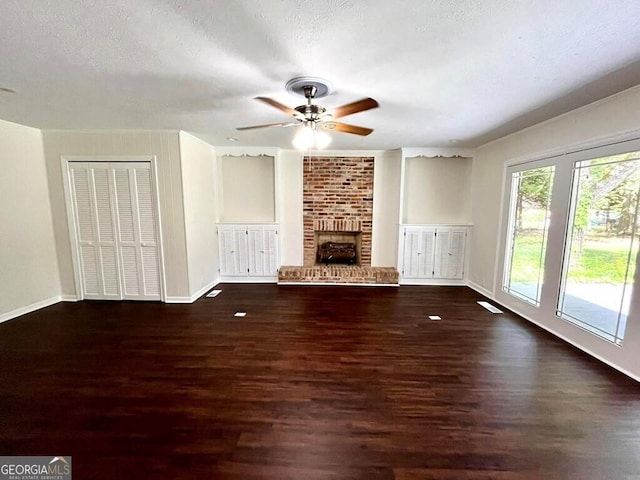 unfurnished living room with ceiling fan, a textured ceiling, a fireplace, and dark hardwood / wood-style flooring