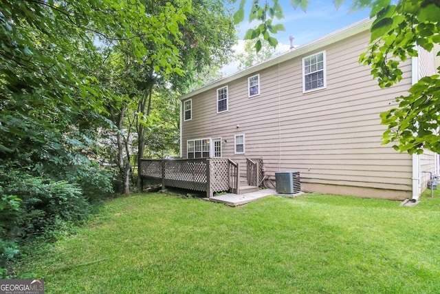 back of house featuring cooling unit, a wooden deck, and a lawn