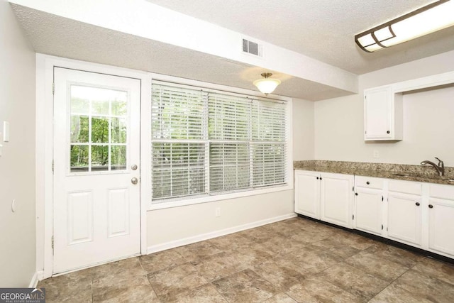 kitchen with white cabinets, tile patterned floors, sink, and a textured ceiling