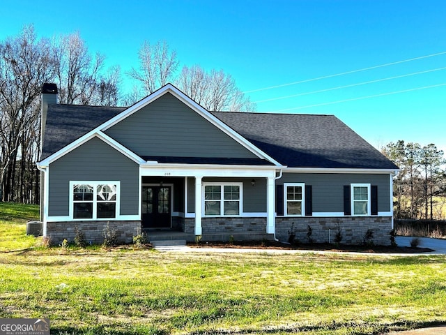 craftsman-style home with a shingled roof, stone siding, a chimney, french doors, and a front lawn