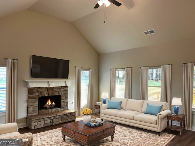 living area with a fireplace, visible vents, ceiling fan, wood finished floors, and high vaulted ceiling