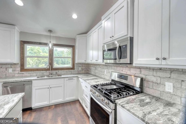 kitchen featuring sink, appliances with stainless steel finishes, hanging light fixtures, light stone counters, and white cabinets