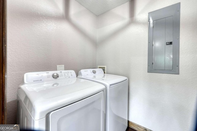 clothes washing area featuring a textured ceiling, electric panel, and washing machine and dryer