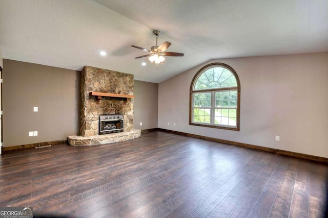 unfurnished living room featuring lofted ceiling, dark wood-type flooring, ceiling fan, a fireplace, and a textured ceiling