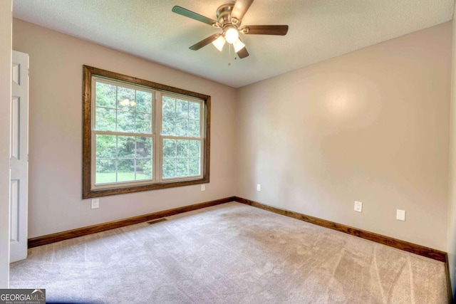 spare room featuring ceiling fan, light colored carpet, and a textured ceiling