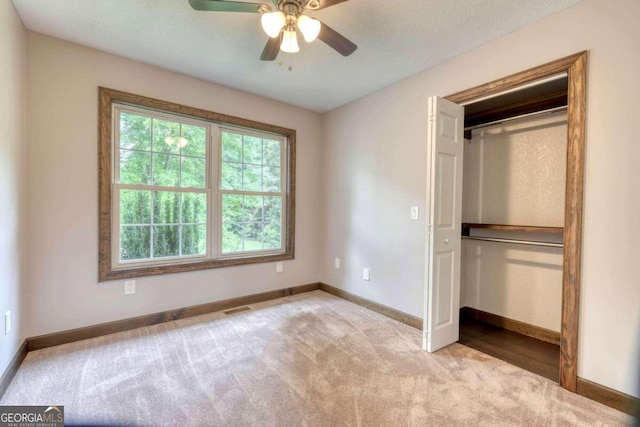 unfurnished bedroom with light carpet, a closet, and ceiling fan