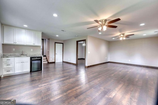 kitchen with sink, white cabinetry, dark hardwood / wood-style floors, light stone countertops, and beverage cooler