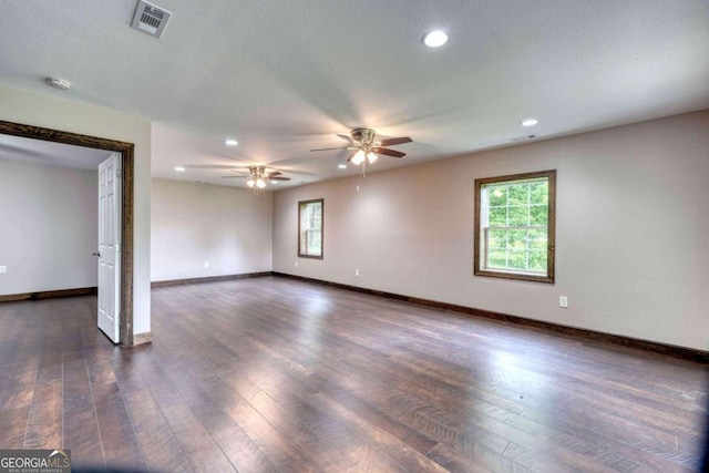 spare room with dark wood-type flooring, a wealth of natural light, a textured ceiling, and ceiling fan