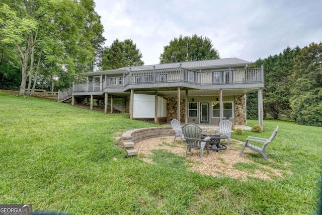 back of house featuring a wooden deck, a fire pit, and a lawn