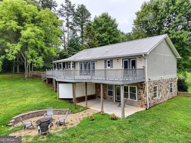 rear view of property featuring french doors, a patio area, a lawn, a deck, and a fire pit