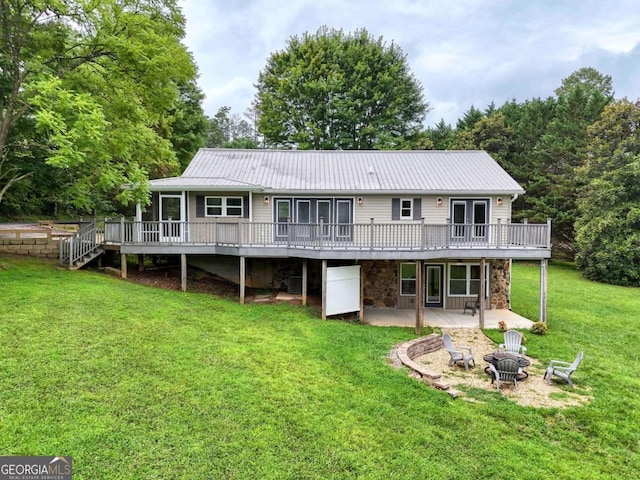 rear view of property with a wooden deck, a patio, a fire pit, and a lawn