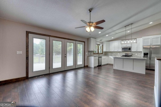 kitchen featuring white cabinetry, decorative light fixtures, a center island, stainless steel appliances, and backsplash