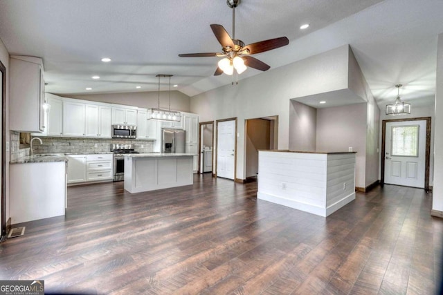 kitchen with vaulted ceiling, pendant lighting, white cabinets, a center island, and stainless steel appliances