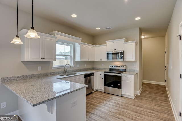 kitchen with pendant lighting, sink, white cabinets, kitchen peninsula, and stainless steel appliances