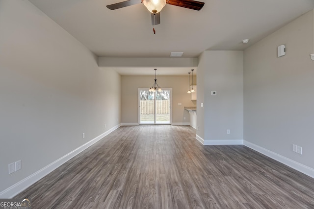 unfurnished living room with ceiling fan with notable chandelier and dark hardwood / wood-style floors