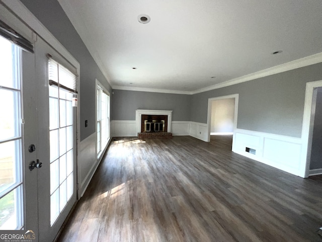 unfurnished living room with a brick fireplace, wood-type flooring, and ornamental molding