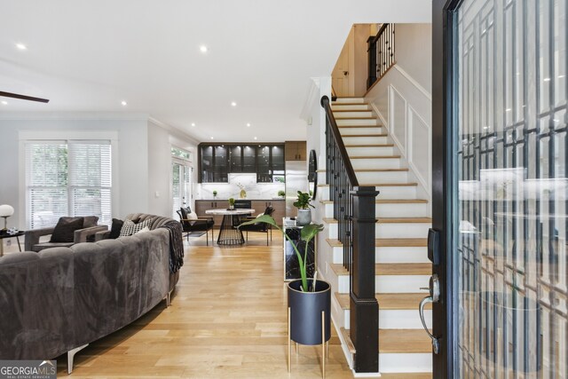 stairs with light hardwood / wood-style flooring and crown molding