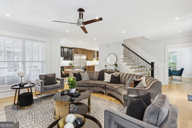 living room with crown molding, light wood-type flooring, and ceiling fan