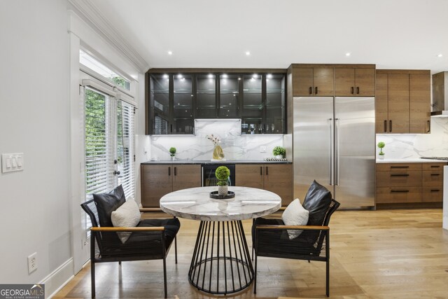 dining room with ornamental molding, light wood-type flooring, and beverage cooler