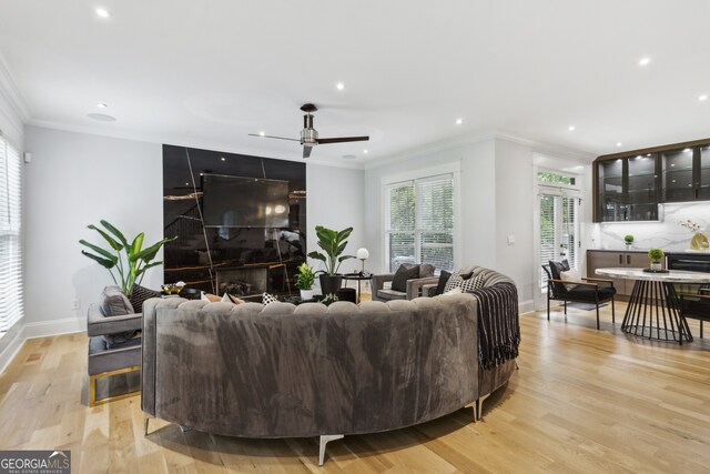 living room featuring crown molding, light wood-type flooring, and ceiling fan