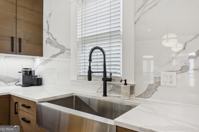 kitchen with sink, light stone countertops, and backsplash