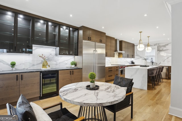 kitchen featuring light hardwood / wood-style flooring, tasteful backsplash, high quality appliances, wine cooler, and wall chimney exhaust hood