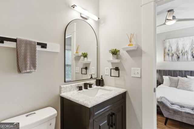 bathroom with hardwood / wood-style floors, toilet, vanity, and ceiling fan