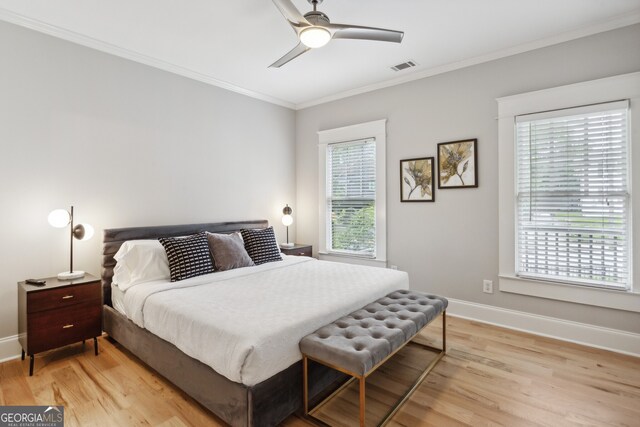 bedroom with multiple windows, light wood-type flooring, ceiling fan, and ornamental molding