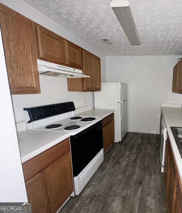 kitchen featuring white appliances, dark hardwood / wood-style floors, and a textured ceiling